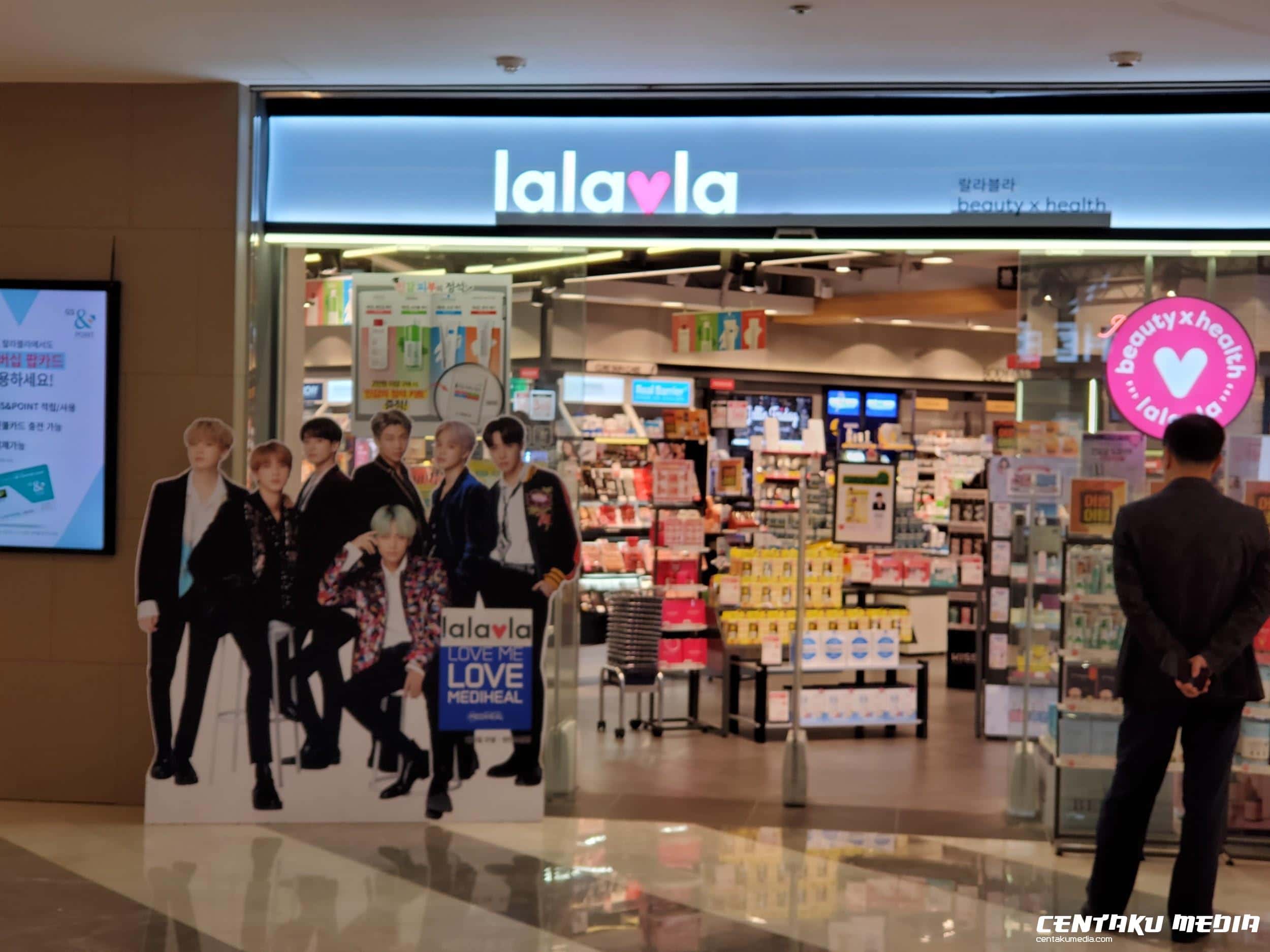 A pop-up poster featuring BTS stands in front of a Heath & Beauty store, Lalavla.